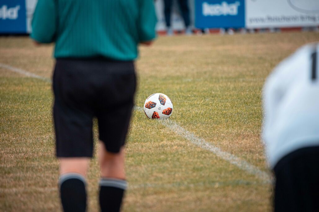 Jugador de camiseta verde conduce el bal&oacute;n en una cancha al aire libre.