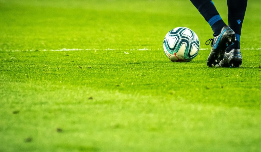 Jugador controla el balón en una cancha de fútbol.