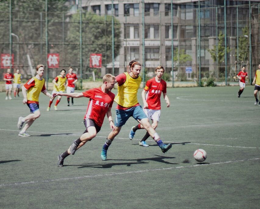 Grupo juega f&uacute;tbol en una cancha cercada.
