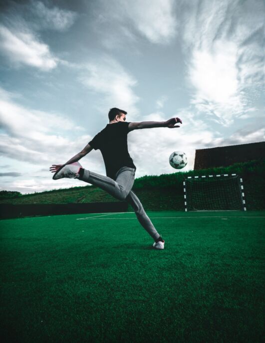 Jugador practica fútbol en una cancha al aire libre.