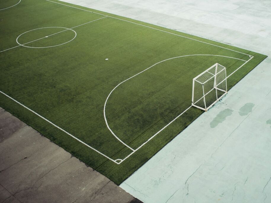 Arco de f&uacute;tbol en una cancha vac&iacute;a de piso verde.