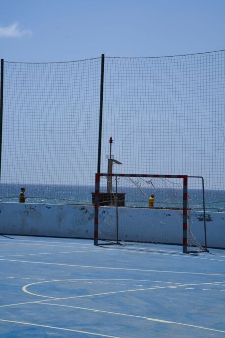 Cancha azul con un arco de f&uacute;tbol junto al mar