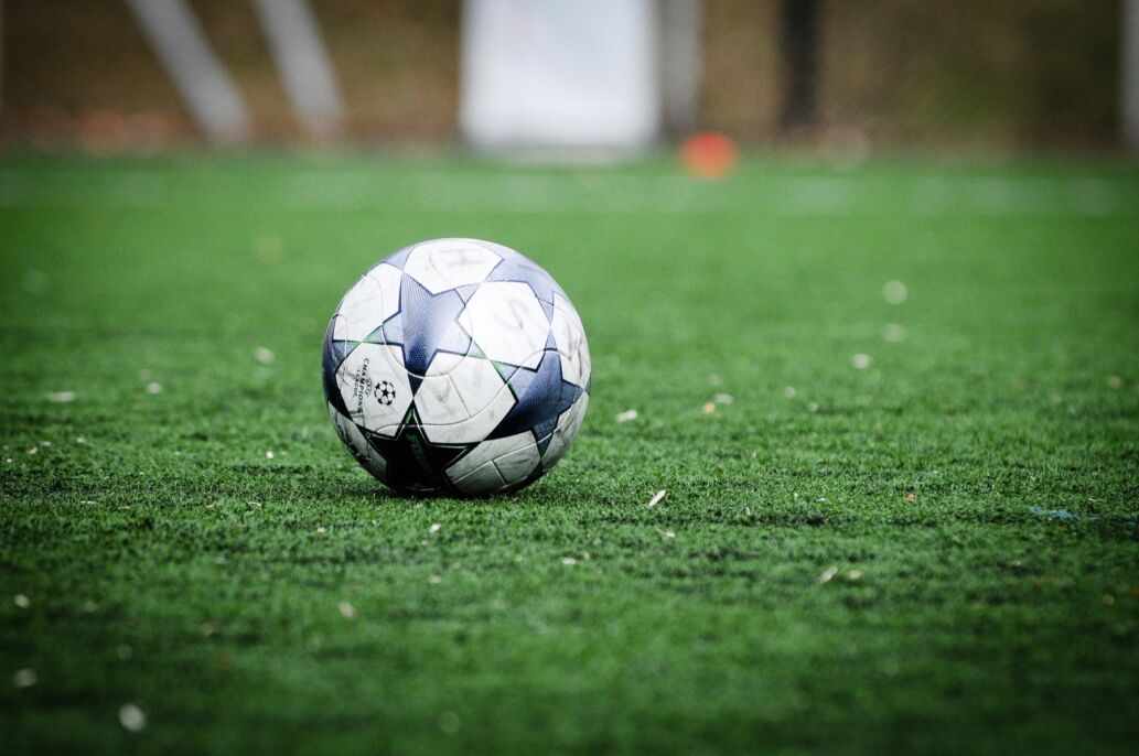 Bal&oacute;n de f&uacute;tbol blanco y azul sobre el c&eacute;sped.