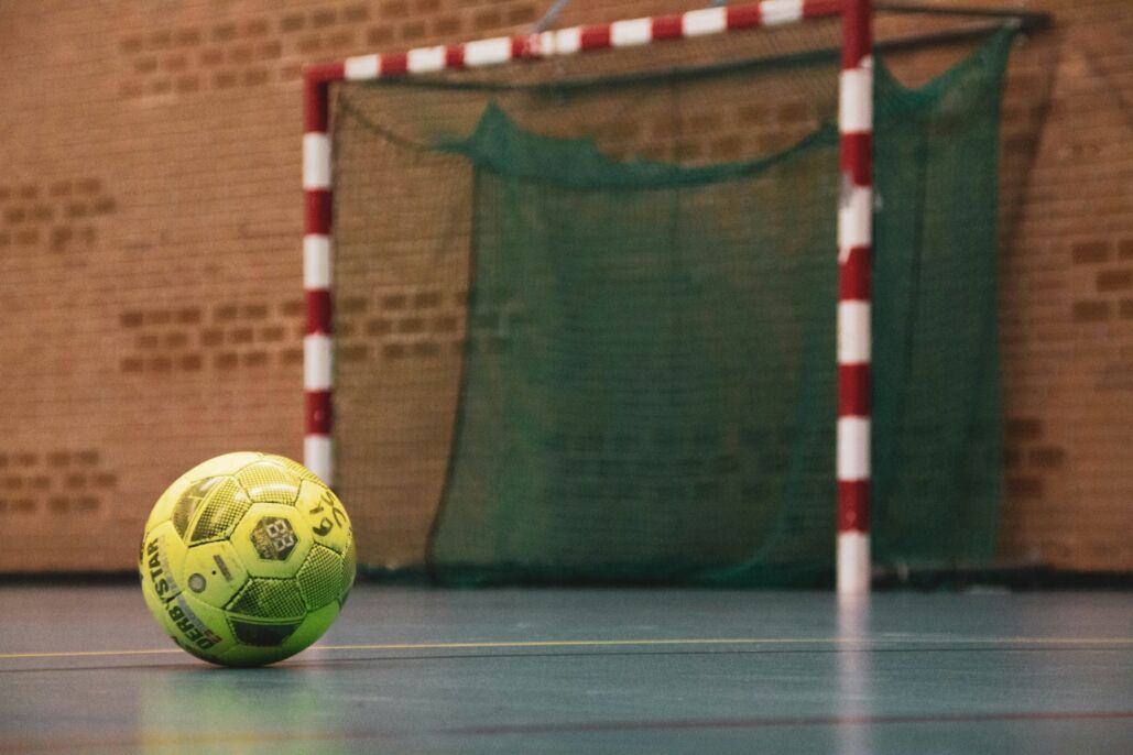 Bal&oacute;n amarillo y negro sobre una cancha interior de f&uacute;tbol sala.