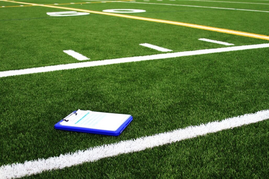 Planilla t&aacute;ctica apoyada junto a la l&iacute;nea de una cancha de f&uacute;tbol.